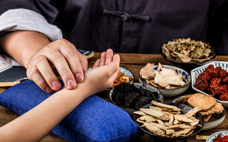 TCM practitioner taking a patient's pulse for diagnosis.