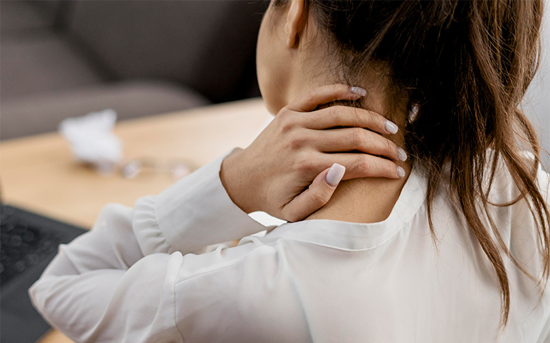 Person holding neck in pain at desk.