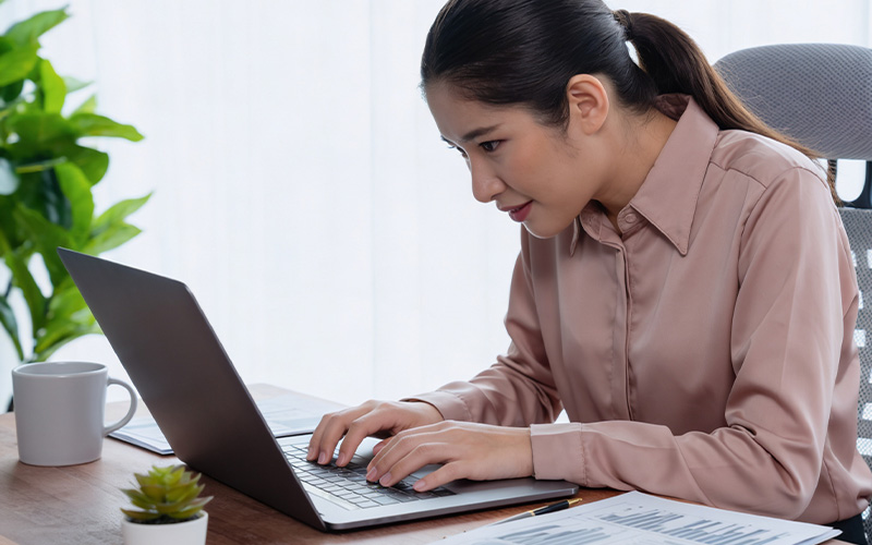 Woman sitting on bed holding her painful lower back.